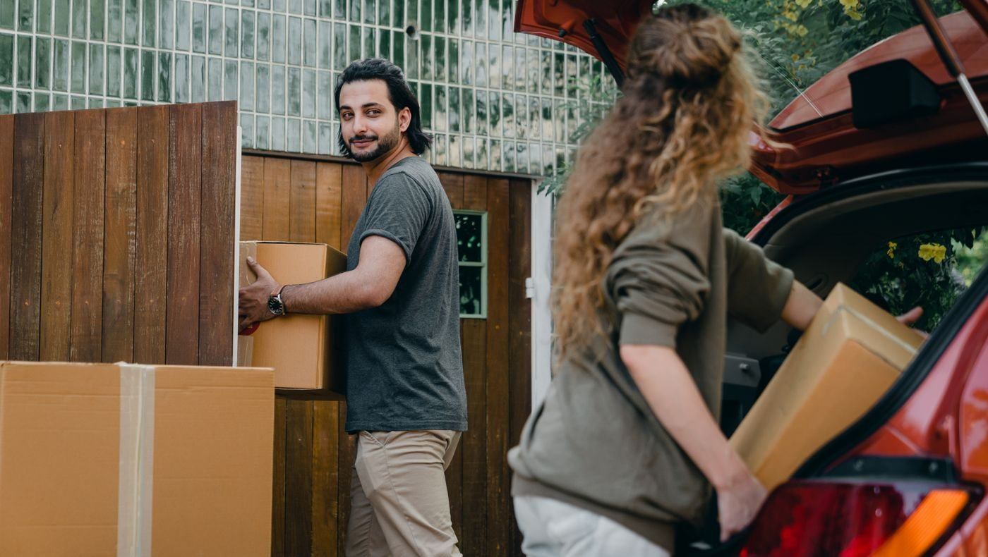 Couple in yard unloading car while moving house — illustrative Pexels photograph